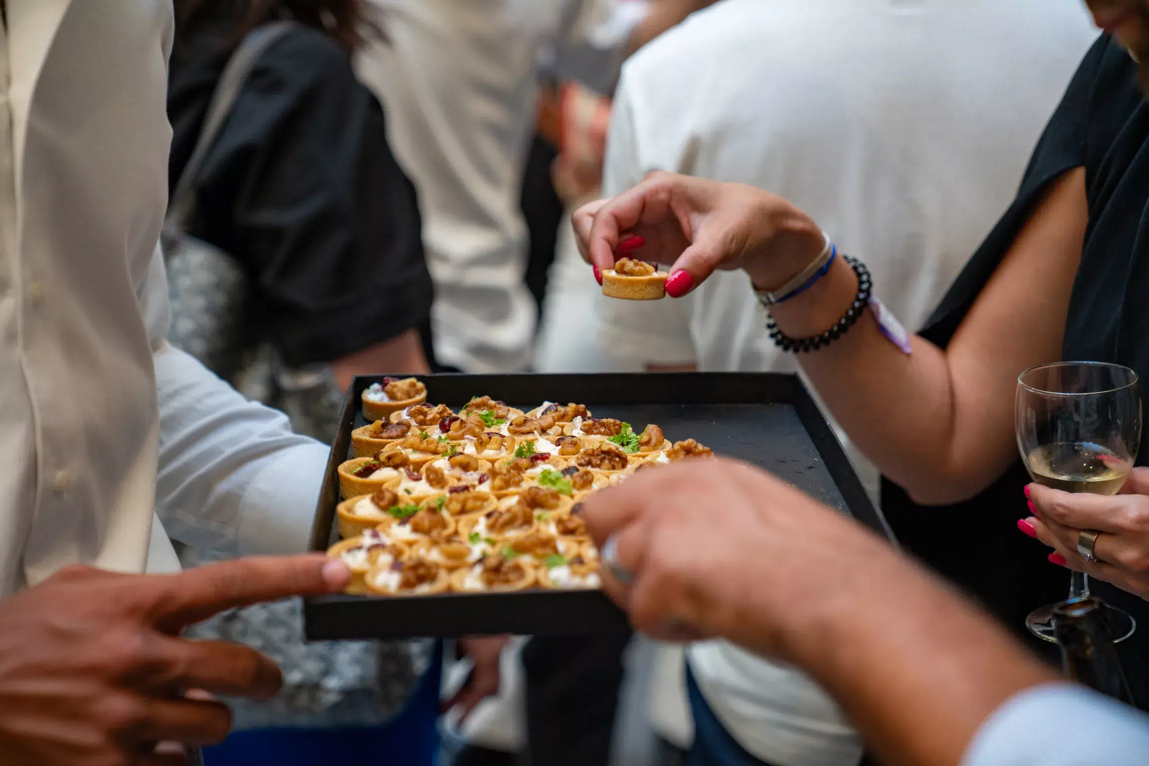 Un serveur Fika présente un plateau de pièces cocktail salées à des convives qui se servent