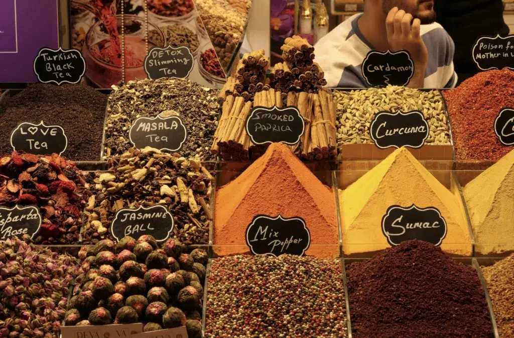 Étal de marché présentant des épices et thés en vrac, dont paprika fumé, curcuma, sumac et mélanges pour cuisine maison.